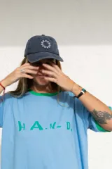 Gorra marrón de algodón con visera curva y bordado frontal con la palabra "HAHA" repetida en círculo.