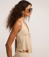 Blusa marrón oscuro con textura plisada, estilo frente única (halter) con escote en V profundo y lazo ajustable en el centro del busto. Presenta un ruedo con volado o efecto nube.