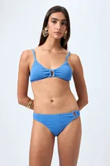 Conjunto de bikini celeste con textura arrugada. El corpiño es de corte triangular con breteles finos y detalle de aro metálico en el centro. La bombacha es de corte clásico con detalle de aro metálico en un lateral.