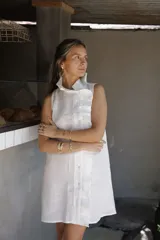 Vestido corto blanco de lino, musculosa con volado en cuello y acceso frontal cruzado. Abotonadura forrada en lino.