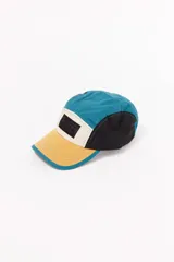Gorro de visera de cinco paneles con diseño color block en azul, amarillo y negro. Presenta un parche con logo en el panel frontal.