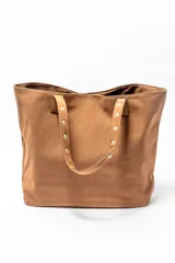 Bolso tipo shopper color negro con apliques de tachas plateadas en los bordes y las asas.