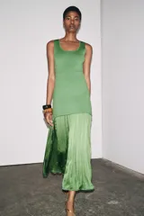 Vestido largo verde con escote redondo y sisas amplias. La parte superior es de punto liso y la falda es plisada de tejido satinado.