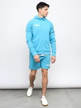 Campera deportiva Umbro celeste con cierre frontal, capucha y detalles de ribetes en mangas y laterales. Logo de la marca estampado en el pecho. Confeccionada en tejido de piqué.