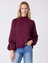 Blusa de gasa satén color bordó, marca Tahari, con cuello alto fruncido y mangas largas abullonadas. La espalda tiene una abertura central con botón.