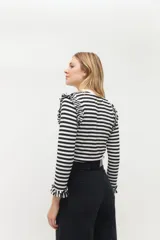 Remera de rayas en blanco y negro con volados en los hombros, ideal para el uso diario.