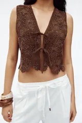 Chaleco marrón de crochet con escote en pico y cierre frontal con lazos.