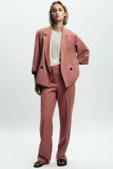 Pantalón de vestir color beige, de tiro alto, con cintura elástica en la parte trasera, bolsillos delanteros y falsos bolsillos de vivo en la parte trasera.