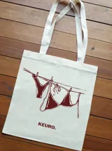 Tote bag de tela color crudo con asas blancas y estampado de un bikini secándose en una cuerda.