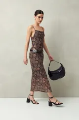 Vestido largo de punto con estampado abstracto en tonos marrones y negros. Tiene breteles finos y corte al cuerpo.