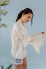Blusa color rosa pálido de tejido fresco y liviano, con cuello alto con lazo y mangas largas con volados.
