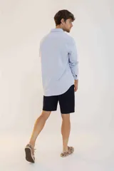 Camisa de hombre color crema, de corte clásico, con cuello abotonado y mangas largas.