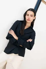 Camisa blanca de algodón con diseño cruzado y mangas largas con volados.