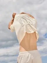 Camiseta color crema de algodón con cuello redondo y calce holgado. Estampa en la espalda con una palmera y texto en gris.