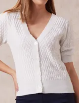 Cárdigan tejido color blanco, marca Tahari. Escote en V, manga corta abullonada con puño y abertura central con botones.