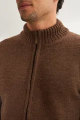 Campera de lana color crema, tejida con cierre delantero, cuello alto y bolsillos delanteros.