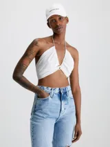 Blusa blanca con textura arrugada, escote halter y cierre anudado en la espalda.
