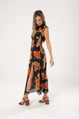 Vestido midi negro con estampado de flores naranjas y beige, espalda descubierta con tres botones en forma de flor, tajo lateral y flecos en el ruedo.