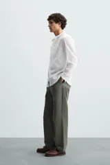 Camisa de algodón blanco con efecto arrugado, cuello mao (tira) y manga larga con puño abotonado. Presenta un corte relajado (relaxed fit) y cierre frontal de botonadura.