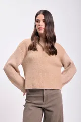 Sweater color beige de punto con cuello alto y mangas ranglan largas. Tejido acanalado vertical.