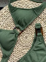 Conjunto de bikini turquesa con textura acanalada, compuesto por un corpiño triangular con argolla central y una bombacha vedetina con argollas en los laterales.