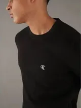 Sweater de punto negro con cuello redondo y logo de la marca bordado en el pecho.