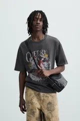 Camiseta negra de corte holgado con cuello redondo y mangas cortas. Estampado frontal con una ilustración de una mujer en un cohete y la leyenda "Cherry Pilot Blush Delight".