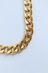 Collar dorado tipo cadena de eslabones metálicos gruesos con cierre de gancho y clip.