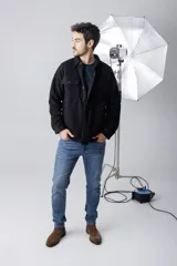 Camisa tipo chaqueta negra de corte recto, con cuello clásico, cierre frontal con botones a presión, dos bolsillos de parche en el pecho y puños abotonados.