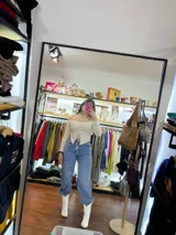 Top color crema con escote off-shoulder, mangas largas y detalle fruncido con cordones en el centro.