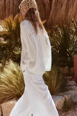 Camisa blanca de manga larga con cuello solapa y bordado de flor en el frente.
