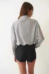 Camisa corta negra de algodón, de corte holgado, con cuello camisero y abotonada al frente.