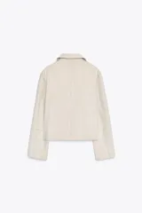 Cazadora color crema de cuello solapa y manga larga. Presenta bolsillos delanteros de plastrón, costuras marcadas y cierre frontal con botones.