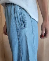 Pantalón de corte amplio en denim oscuro, con detalles de costura y cintura ajustable.