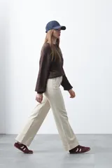 Pantalón negro de tiro alto, corte recto y silueta clásica. Presenta costuras verticales marcadas en la parte delantera de las piernas.