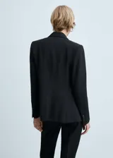Blazer azul marino con cuello de pico y solapa, hombros estructurados, diseño entallado y dos bolsillos de ribete en la parte delantera.