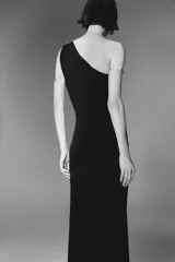 Vestido midi negro de punto, con escote asimétrico, manga sisa y aplique dorado en el hombro.