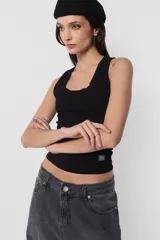 Musculosa blanca de algodón con lycra, corte ajustado y detalle de plastisol transparente en el ruedo.