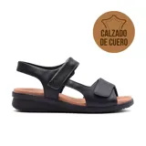Sandalias de cuero negro Usaflex modelo Judith, con ajuste de velcro en el empeine y tobillo. Suela marrón con tecnología Low Impact para absorción de impactos.