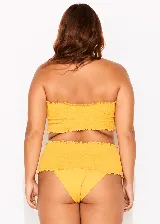 Conjunto de bikini amarillo con corpiño bandeau con volados y bombacha de tiro alto con volados.