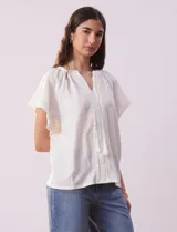 Blusa blanca texturada, marca Sabrina Lauren, con cuello a la base, escote en V con puntilla y lazo, mangas cortas amplias y aplique de puntilla.