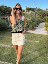 Top negro con estampado dorado, breteles de cuero y espalda tejida.