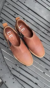 Zapato bajo color beige con textura de reptil, con detalle de cuero marrón en el talón.