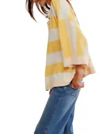 Remera de corte extragrande a rayas horizontales amarillas y blancas, confeccionada en jersey de peso medio, con textura suave y hombros caídos para un look relajado. Presenta un cierre frontal parcial con botón y terminaciones simples.