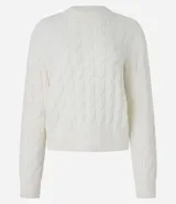 Suéter de punto pesado color crema, con textura trenzada y cuello redondo.