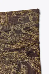 Falda midi de tiro alto con estampado paisley en tonos marrones y dorados. Presenta cintura con drapeado lateral y bajo asimétrico evasé. Cierre con cremallera oculta en la costura.