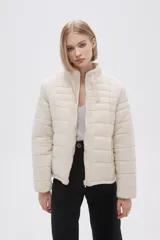 Campera puffer color crema con cuello alto y cierre frontal.