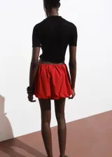 Jersey de punto fino color negro, manga corta, cuello perkins y diseño crop ajustado.