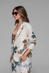 Conjunto de dos piezas compuesto por un blazer de lino con estampado floral en tonos celestes, marrones y blanco, de calce holgado, mangas largas y solapas. Se combina con un pantalón palazzo a juego de pierna ancha y cintura cómoda.