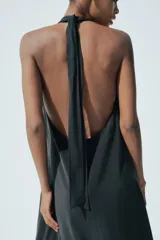 Vestido midi negro de tejido fluido, con cuello halter que se ata al cuello, escote en V y espalda descubierta.